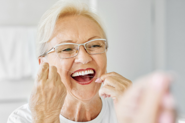 A woman flossing her fixed dentures.